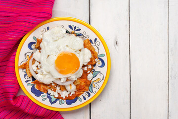 Mexican red chilaquiles with fried egg on white background