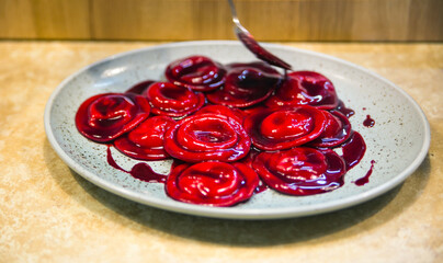 ravioli in red sauce are served by the chef on a plate