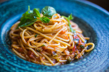 pasta with tomato sauce and meat served on a blue plate