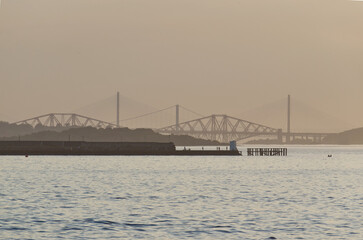 People fishing on the Granton Harbour Pier overlooking the Firth of Forth Bridges at sunset