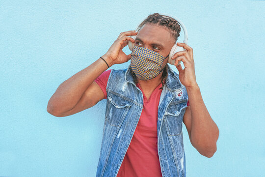 Boy With Headphones On Listening To Music In Covid-19 Time With Face Mask And Keeping The Social Distance  