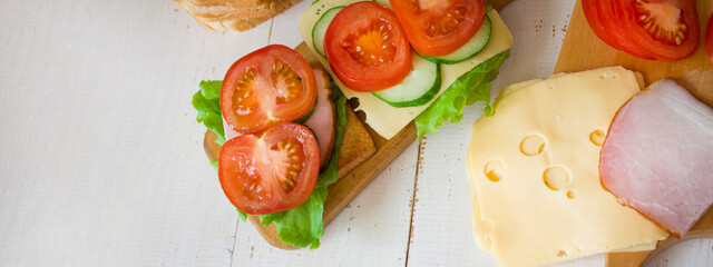 Cheese and ham toasts. Tomatoes and greens. Healthy eating concept. Banner. View from above....