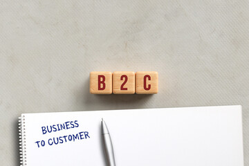 cubes with acronym B2C and explanation BUSINESS TO CUSTOMER on a notepad on paper background