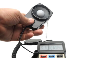 Close up a hand catching a light probe of a LUX meter for measurement.