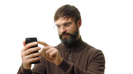 Confident businessman holding smartphone in hand and typing text message. Bearded man using cell phone on white background