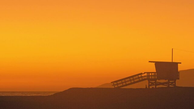 Malibu lifeguards watchtower during a red, orange-saturated sunset on the beach