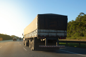 Truck body covered with tarpaulin on the road during sunset