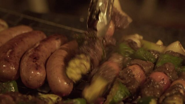 Close-up of person flipping food with serving tongs on barbecue at beach during night - Luang Prabang, Laos