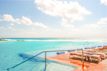 big infinity pool with salt water in the Caribbean sea in bright sunny afternoon. Summer tropical ocean location getaway. Turquoise blue water and orange red deck chairs. hotel no people