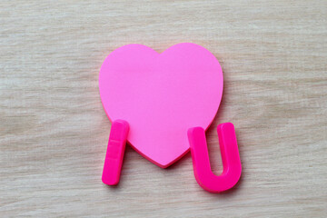Letters I and U with a blank symbolic heart shaped sticker. Short Message I love you
