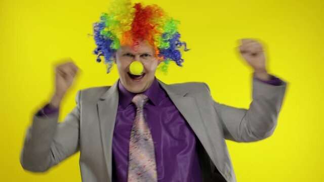 Clown businessman entrepreneur in wig dancing, celebrate, making silly faces