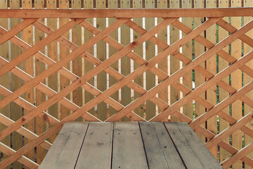 Wooden lattice of a gazebo with a wooden table and a fence from vertical boards. Eco-friendly patio close up.