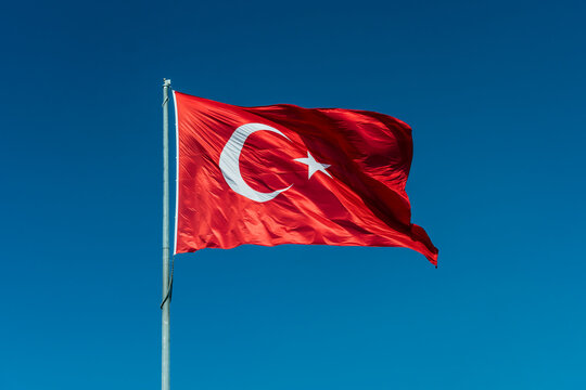Turkish flag waving in blue sky.