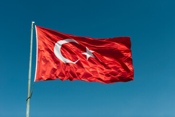 Turkish flag waving in blue sky.