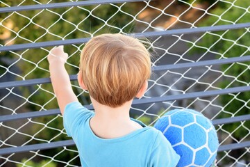 Two years old blond boy playing at the terrace during quarantine for coronavirus. There is a security net on the balcony. 21st March, 2020, Buenos Aires, Argentina.