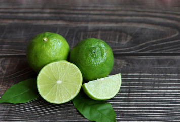 Natural fresh lime with green leaves on wooden background.