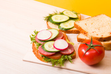 a sandwich of vegetables and diet sausage on a wooden cutting board, wooden table, bread and vegetables in the background, healthy breakfast concept, copy space