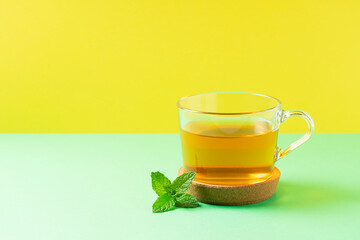 Mint tea and mint leaves placed on a yellow and green background