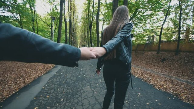 Young pretty happy woman is smiling in autumn park. Total black look. Slow motion. Copy space. 4K.