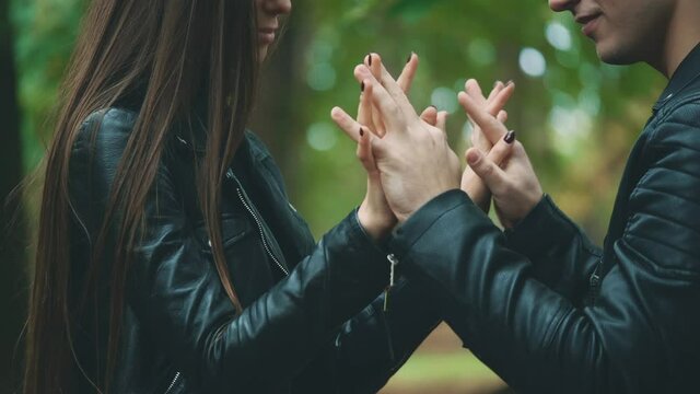 Couple is holding, patting and warming up hands during cold autumn day. Handsome guy is kissing his girlfriend. Close up. Blurred background. Crop. 4K.