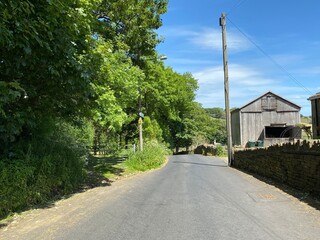 Country road lined with trees, and a wooden building, and a blue cloudy sky in, Thornton, Bradford, UK