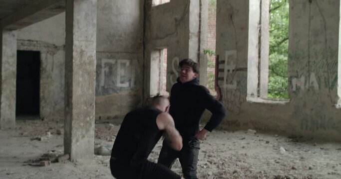 Two angry men perform a free fighting with skilled in an abandoned building