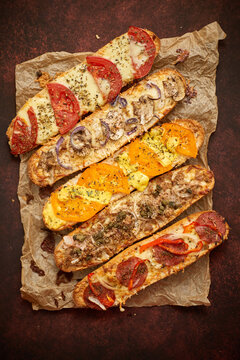 Assortment of various toppings baked sandwiches. With melted cheese, vegetables, tuna, olives spices