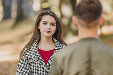 Rear view of a boy and girl looking at him with such facial expression as if she is going to tell him something that can hurt him.