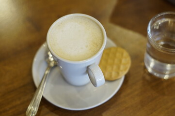 Taza de café express servido en la mesa con una galleta a su lado