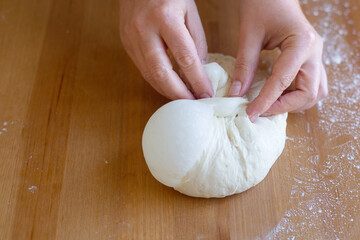Woman's hands makes the straight dough method. On the sourdough are bubbles, good gluten. The process of making fresh homemade elastic dough for baking pizza or bread. Easy to cook together at home. 
