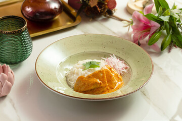 Chicken breast in a sauce with boiled rice in a plate, lunch in a cafe
