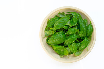Bowl of basil leaves on white background.