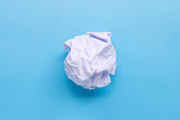 Crumpled paper ball on blue background.