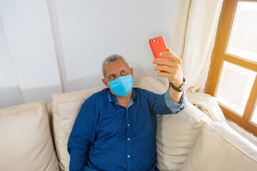 older man having a video call on his cell phone while at home on covid19
