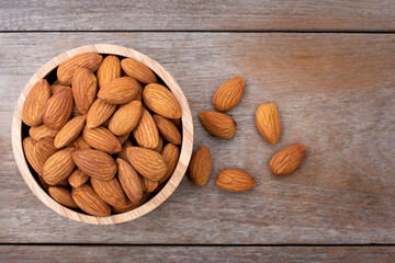 Closeup almond nuts in wooden bowl isolated on rustic wood table  background. Overhead view. Flat lay.