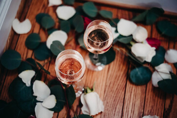 Obraz na płótnie Canvas Glasses of rose wine surrounded by petals