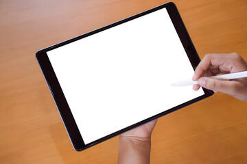 Mockup image of businessperson  hand holding black tablet computer pc with empty white screen and using pencil for writing or drawing on it. Overshoulder view.