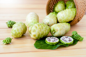 Noni fruits or Morinda citrifolia( known as indian mulberry, cheese fruit) in bamboo wooden basket isolated on white background.Top view. Flat lay.