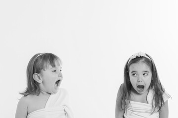 two little girls with their mouths wide open on a white background. The children are playing. the concept of education , childhood, emotions, dentistry, surprise, friendship. Copy space