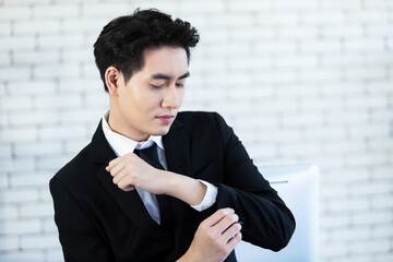 Portrait of Happy mood asian young businessman puts on cufflinks wear a business suit of man in...