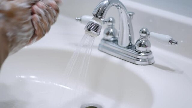 african american man washing hands at home in white bathroom sink
