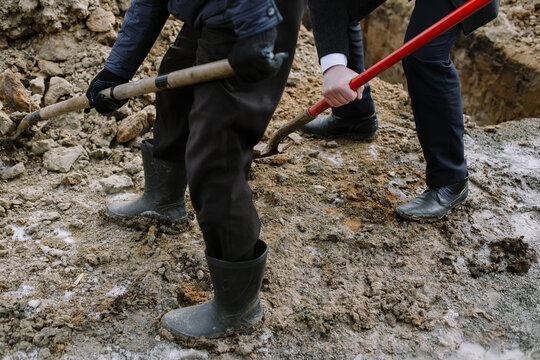 A businessman and a worker dig a hole, shovels the soil to cover the grave and bury the dead.