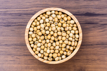 Closeup soy beans in wooden bowl  isolated on wood background. Overhead view. Flat lay.