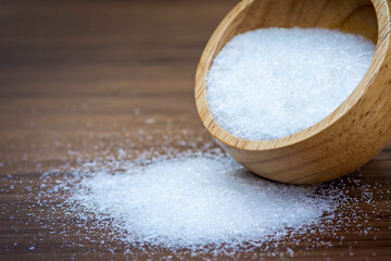 Monosodium glutamate ( MSG ) in wooden bowl pouring on rustic wooden table background. Selective focus.