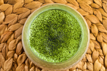 Iced Dalgona Matcha Latte with flower on a wicker background. Top view