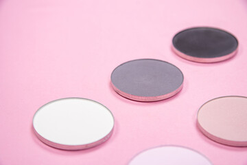 Pattern of eye shadows of different colors on a pink background