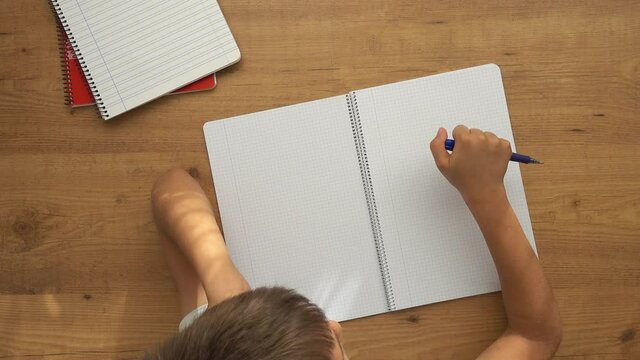 Kid sit at table with open notebooks and tapping with pen. Education, learning difficulties, school homework, learning at home