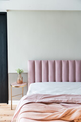 Cozy Pink Bedroom corner with baby pink velvet fabric bed decorated by blanket, pillows and pink floor lamp with two-tone beige painted wall on the background/interior bedroom furniture concept