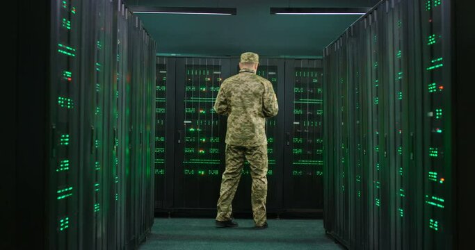 Caucasian military male officer coming in the server room with tablet device in hands, working with secret data and anti-terrorism information. Cybersecurity concept.