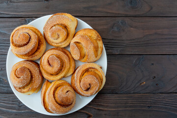 Freshly baked cinnamon buns on a white platter. Crispy buns